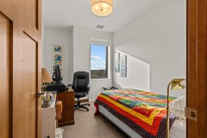 Bedroom and home office setup with colorful quilt and window view at Cedar Crest senior apartment