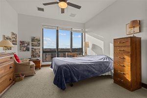 Primary bedroom with tall windows, ceiling fan, and natural light in Cedar Crest Independent Apartment.