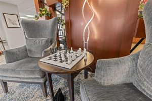 Cozy chess corner with two gray armchairs and a chessboard at Cedar Crest senior living community