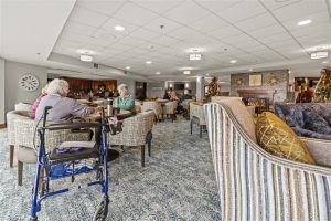 Residents enjoy coffee and conversation in a cozy lounge area at Waterford Place Apartments, featuring comfortable seating, a fireplace, and warm decor.