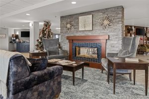 Elegant fireplace lounge with armchairs and Christmas decorations at Cedar Crest Retirement Community.