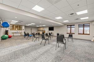 Spacious fitness and wellness room at Waterford Place Apartments set up for group exercise classes with chairs and yoga balls.